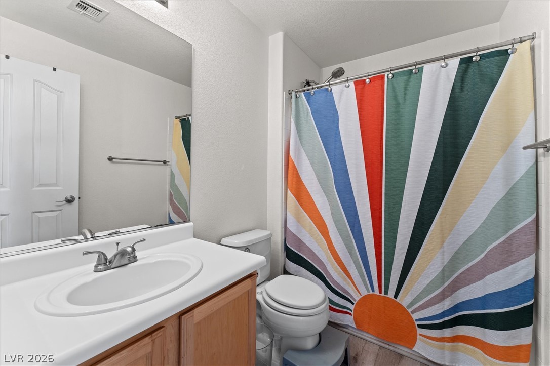 503 Rafkin Place Henderson, NV 89052 - Photo 13 of 18 A well-lit primary bathroom features a white vanity and a colorful shower curtain.