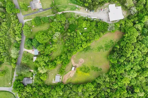 an aerial view of residential house with outdoor space and trees all around