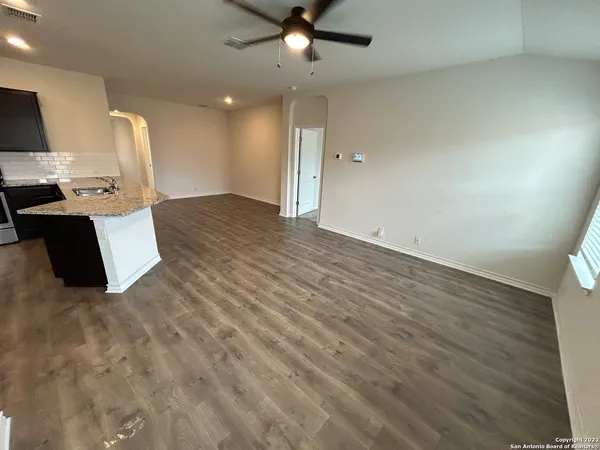 an empty room with wooden floor and a ceiling fan