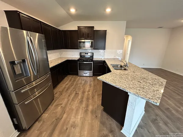 a kitchen with kitchen island granite countertop stainless steel appliances and wooden cabinets