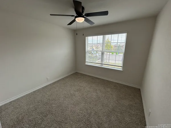 an empty room with a window and a fan