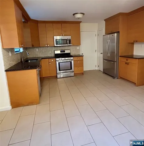 a kitchen with stainless steel appliances a refrigerator a stove a sink a counter top space and cabinets