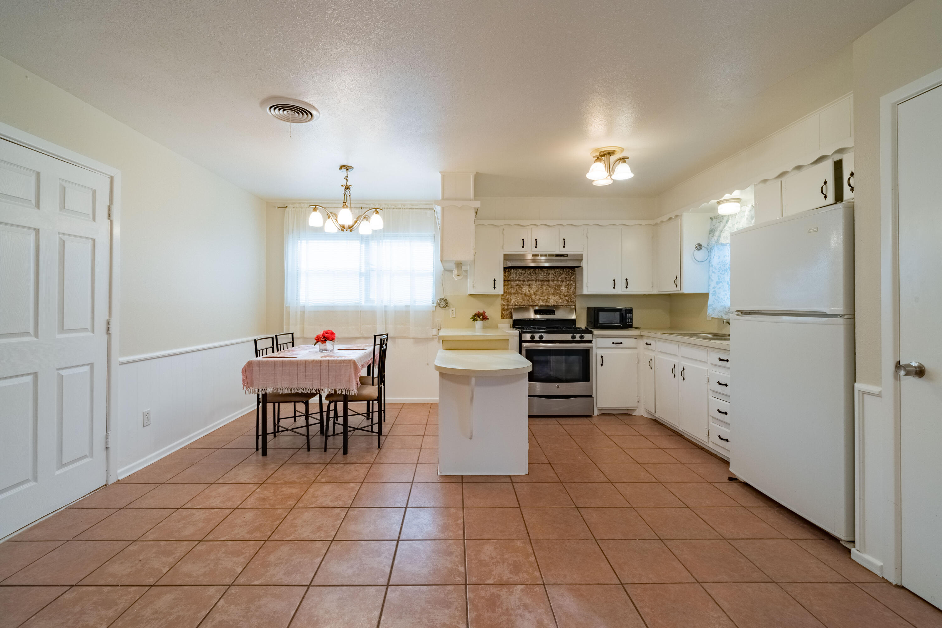 5202 47th Street Lubbock, TX 79414 - Photo 4 of 15 a kitchen with a refrigerator a microwave and dining table