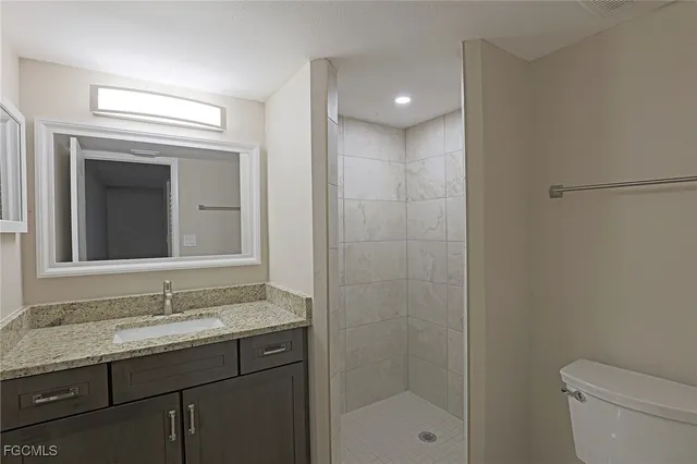 a bathroom with a granite countertop sink a toilet and a mirror