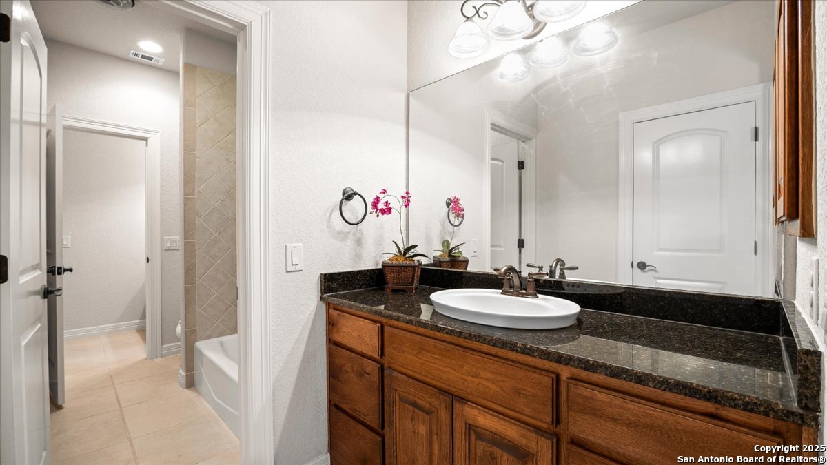 8018 Canham Ranch Garden Ridge, TX 78266 - Photo 27 of 51 a bathroom with a granite countertop sink and a mirror