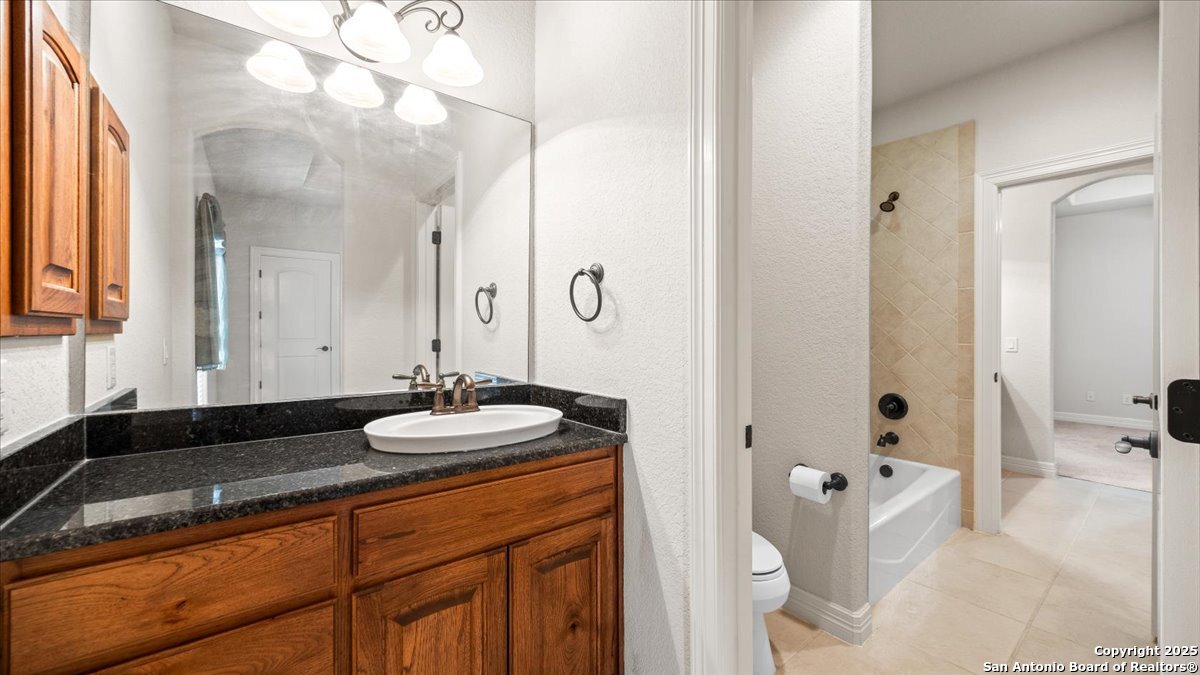 8018 Canham Ranch Garden Ridge, TX 78266 - Photo 28 of 51 a bathroom with a granite countertop sink a toilet and a large mirror