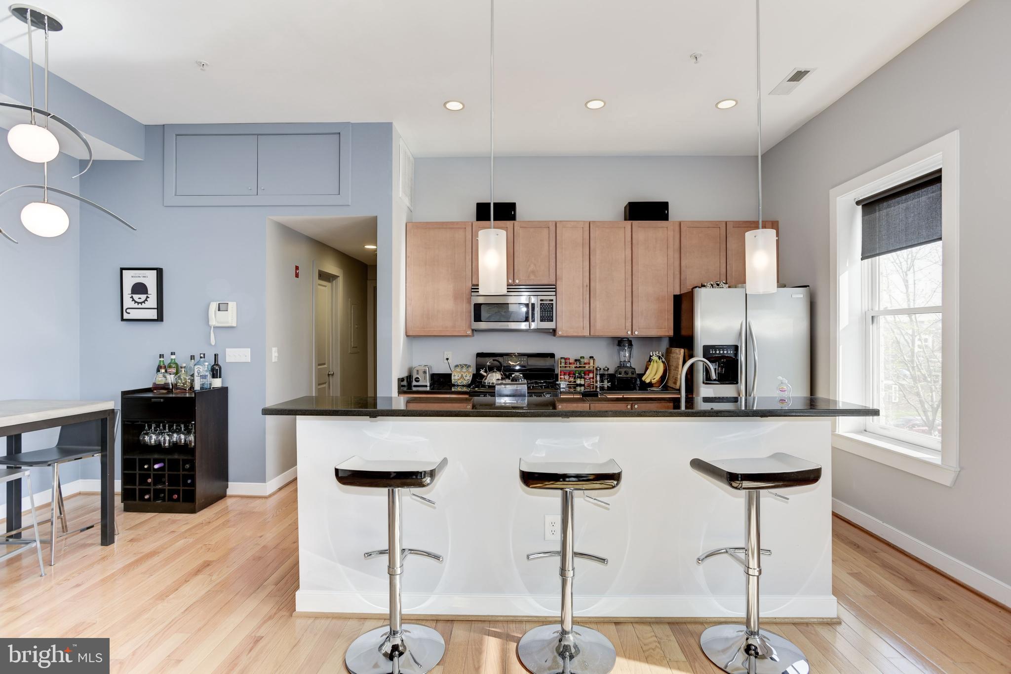 1240 4th Street Northwest, Unit 200 Washington, DC 20001 - Photo 7 of 18 a kitchen with granite countertop a counter space chairs cabinets and stainless steel appliances