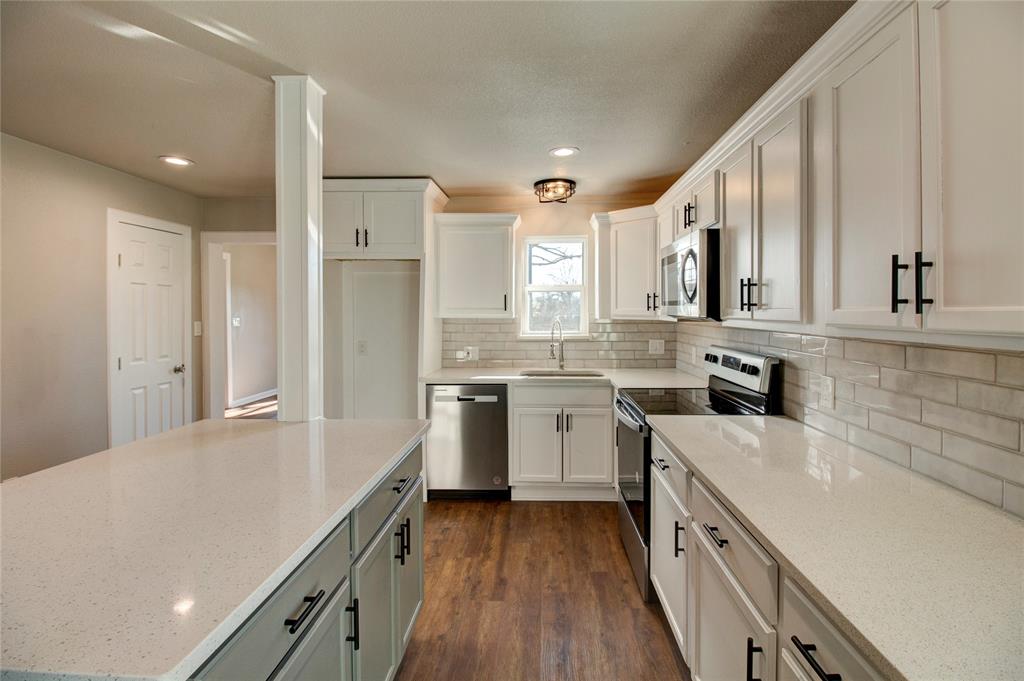 a kitchen with a sink dishwasher a refrigerator and cabinets with wooden floor
