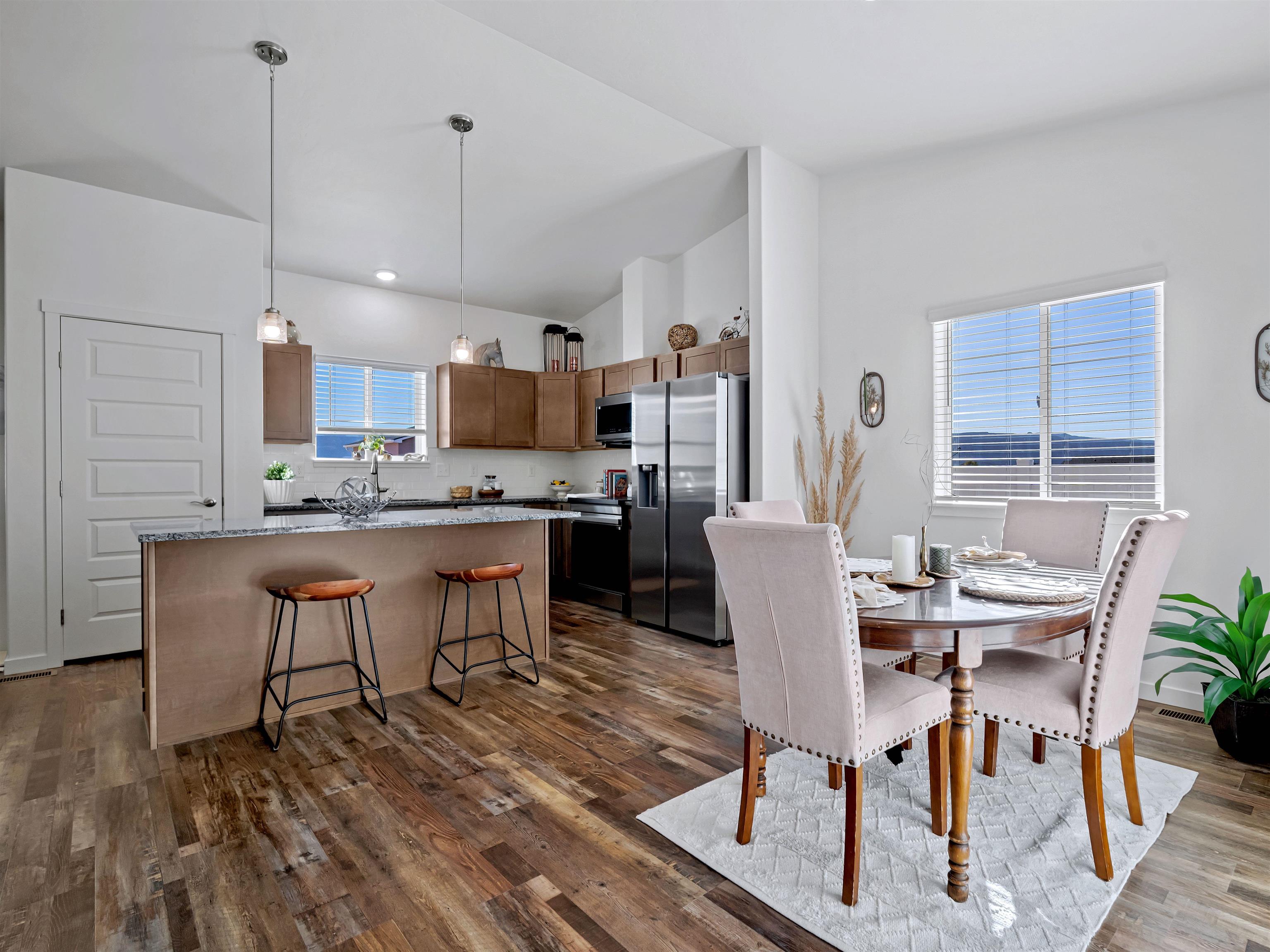 2147 Moon River Road Grand Junction, CO 81505 - Photo 13 of 34 a kitchen with stainless steel appliances kitchen island granite countertop a dining table chairs and a refrigerator