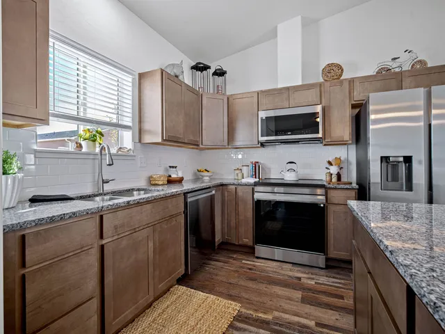 a kitchen with stainless steel appliances granite countertop a sink stove and refrigerator