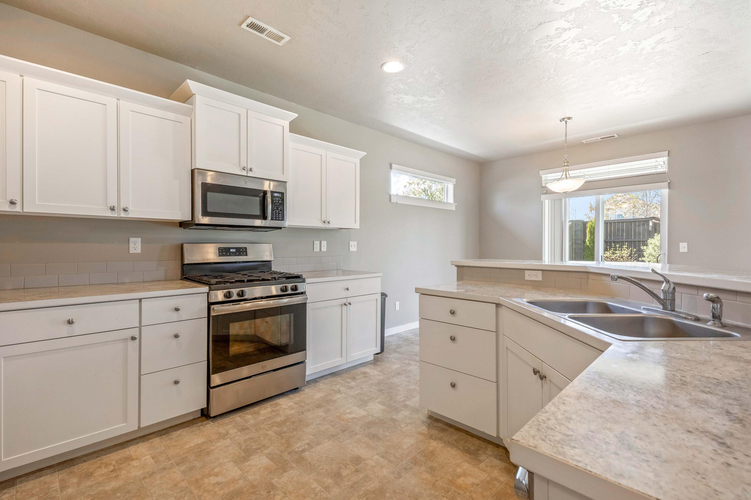 2510 Northwest Hemlock Way Redmond, OR 97756 - Photo 9 of 32 a kitchen with stainless steel appliances granite countertop a sink and white cabinets