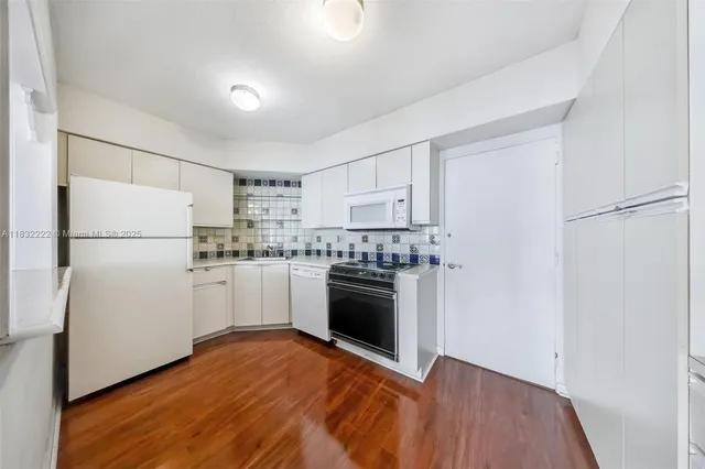 a kitchen with a refrigerator stove and white cabinets