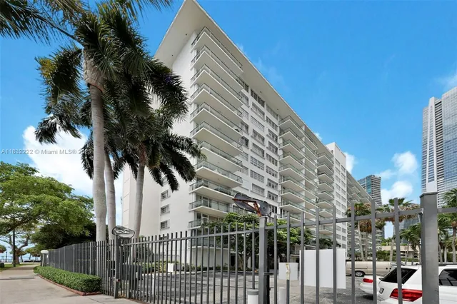 a view of a white building with a palm tree in the background