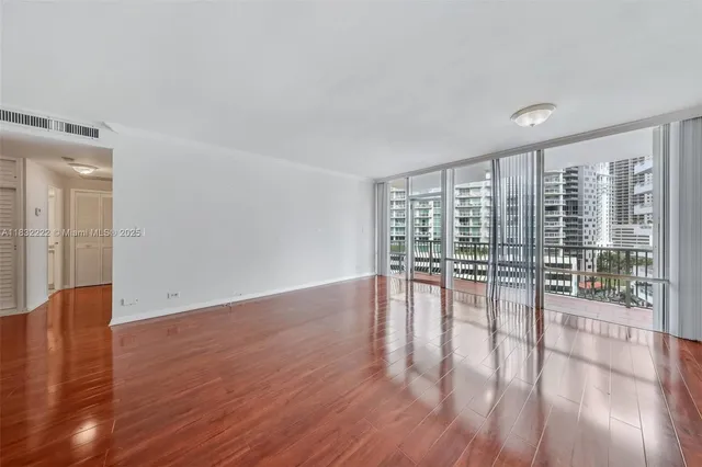 a view of empty room with wooden floor and floor to ceiling window