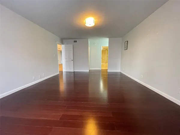 a view of an empty room with wooden floor and stairs