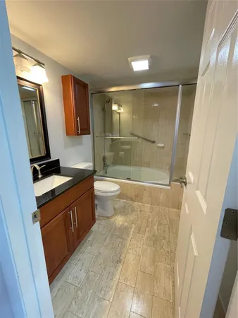 a bathroom with a sink a toilet a mirror and shower