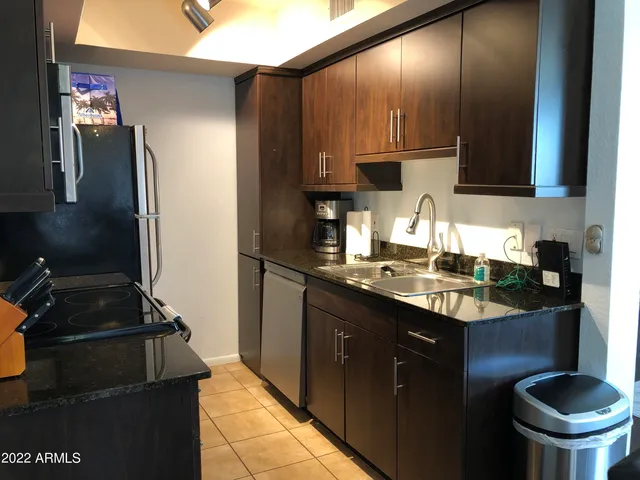 a kitchen with granite countertop stainless steel appliances a sink stove and refrigerator