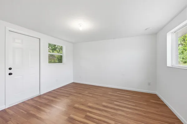 a view of empty room with wooden floor and fan