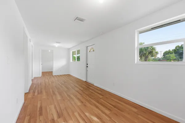 a view of empty room with wooden floor and fan
