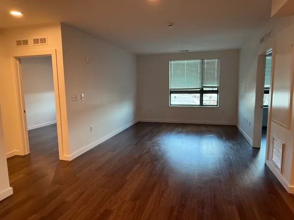 an empty room with wooden floor and windows