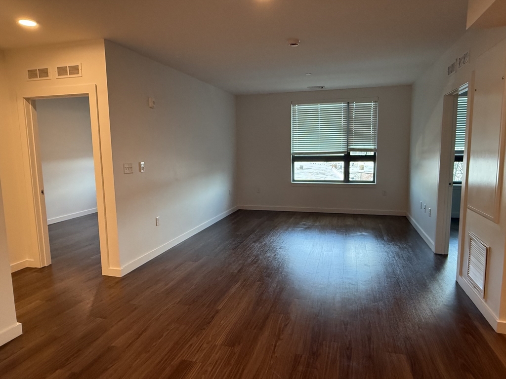 466 River Street, Unit 308 Boston, MA 02126 - Photo 2 of 17 an empty room with wooden floor and windows