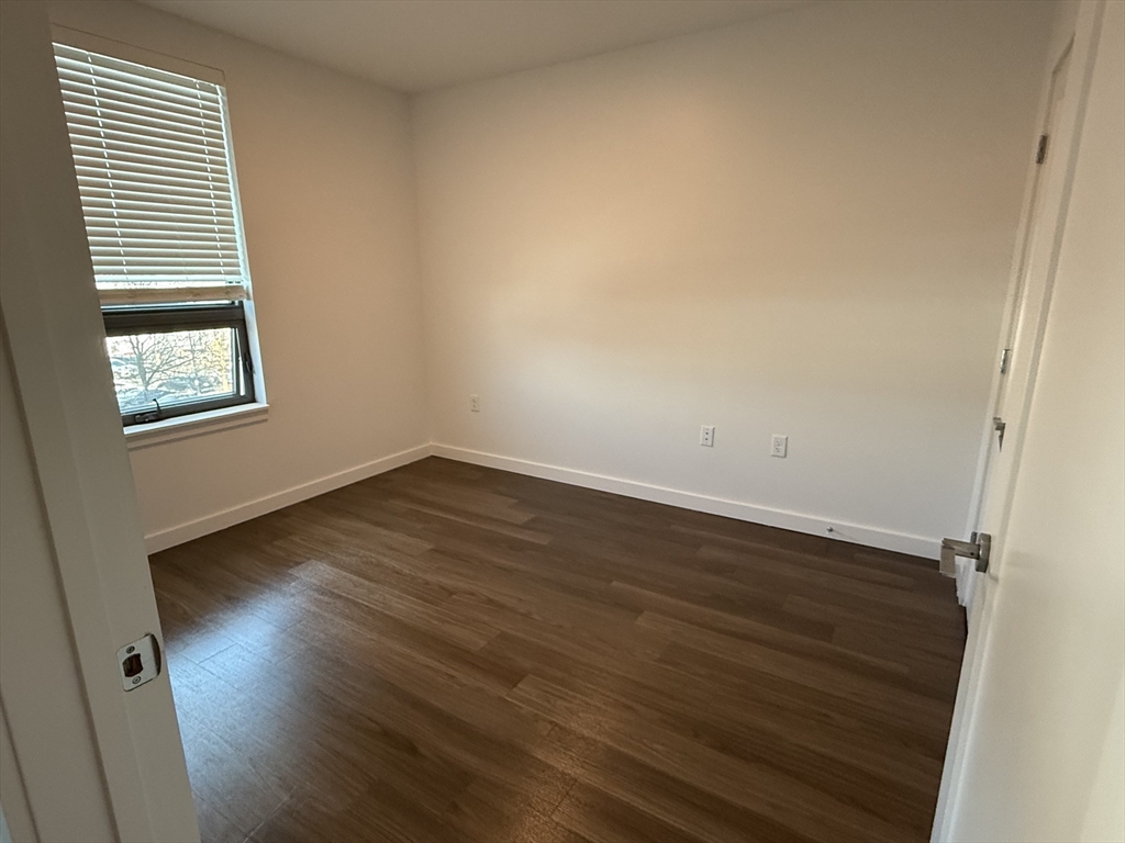466 River Street, Unit 308 Boston, MA 02126 - Photo 3 of 17 an empty room with wooden floor and windows