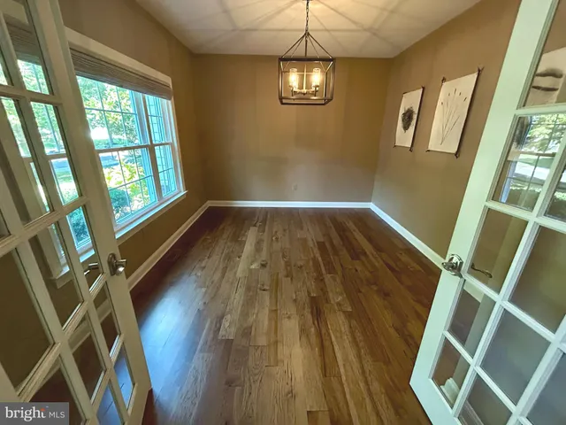 a view of an empty room with wooden floor and window