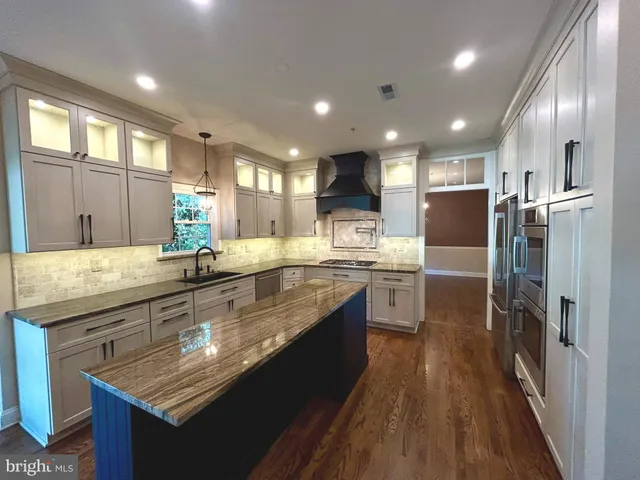 a large kitchen with large counter top space a sink stainless steel appliances and cabinets