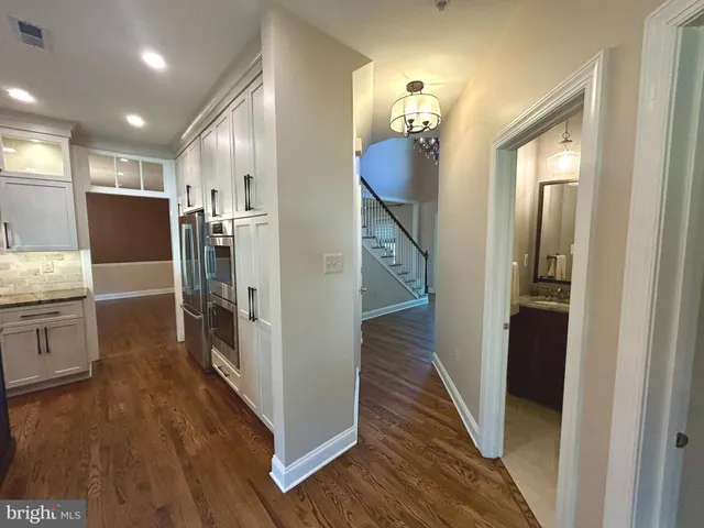 a view of a hallway with wooden floor cabinets and a kitchen