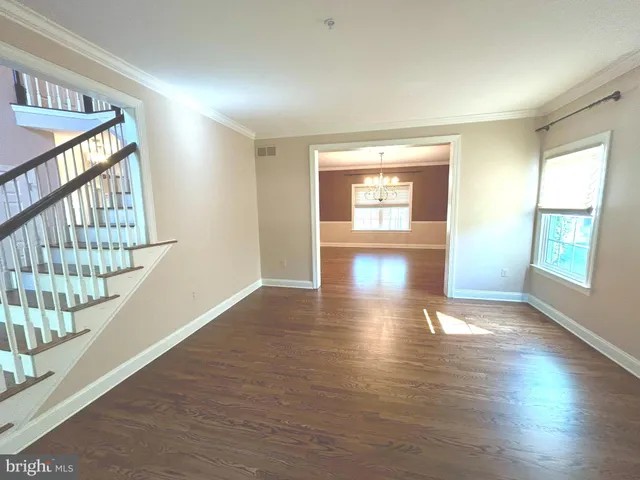 a view of an empty room with wooden floor and windows