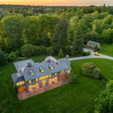 a view of a big house with a big yard and large trees