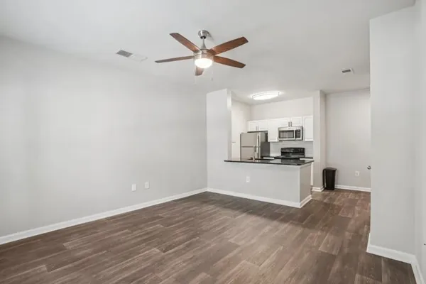 an empty room with wooden floor a ceiling fan and windows