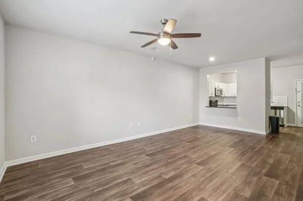 a view of an empty room with wooden floor and a window
