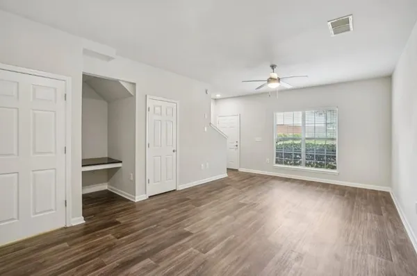an empty room with wooden floor fan and windows