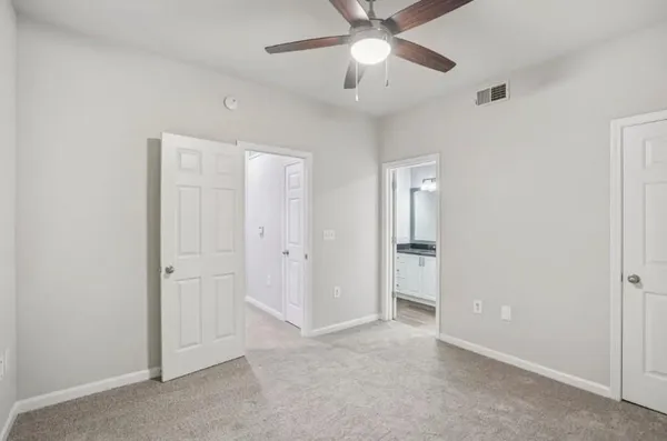 an empty room with closet and a ceiling fan