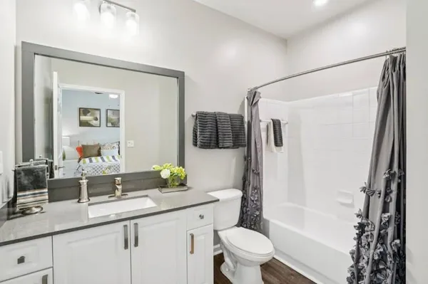 a bathroom with a granite countertop sink a toilet a mirror and shower