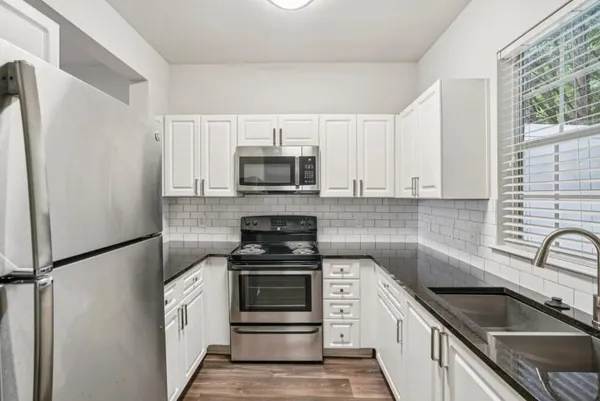 a kitchen with granite countertop a sink stove and microwave