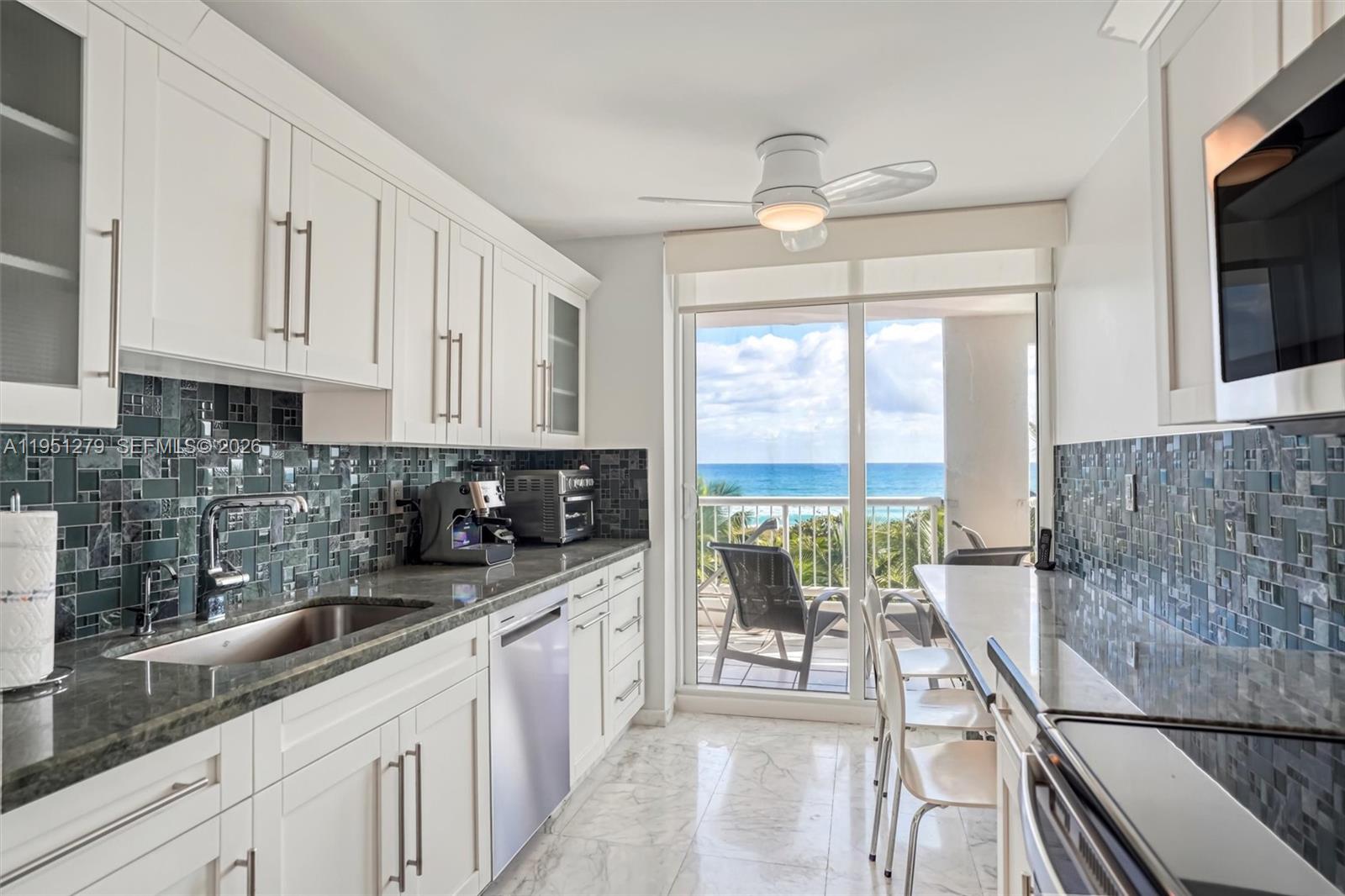 9341 Collins Avenue, Unit 201 Surfside, FL 33154 - Photo 2 of 34 a kitchen with granite countertop a large window a sink and cabinets