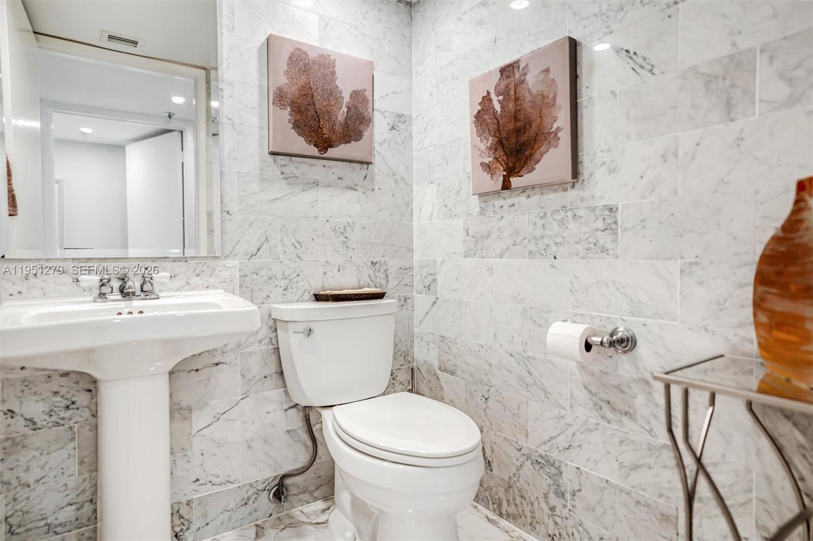 9341 Collins Avenue, Unit 201 Surfside, FL 33154 - Photo 23 of 34 a bathroom with a toilet sink and mirror