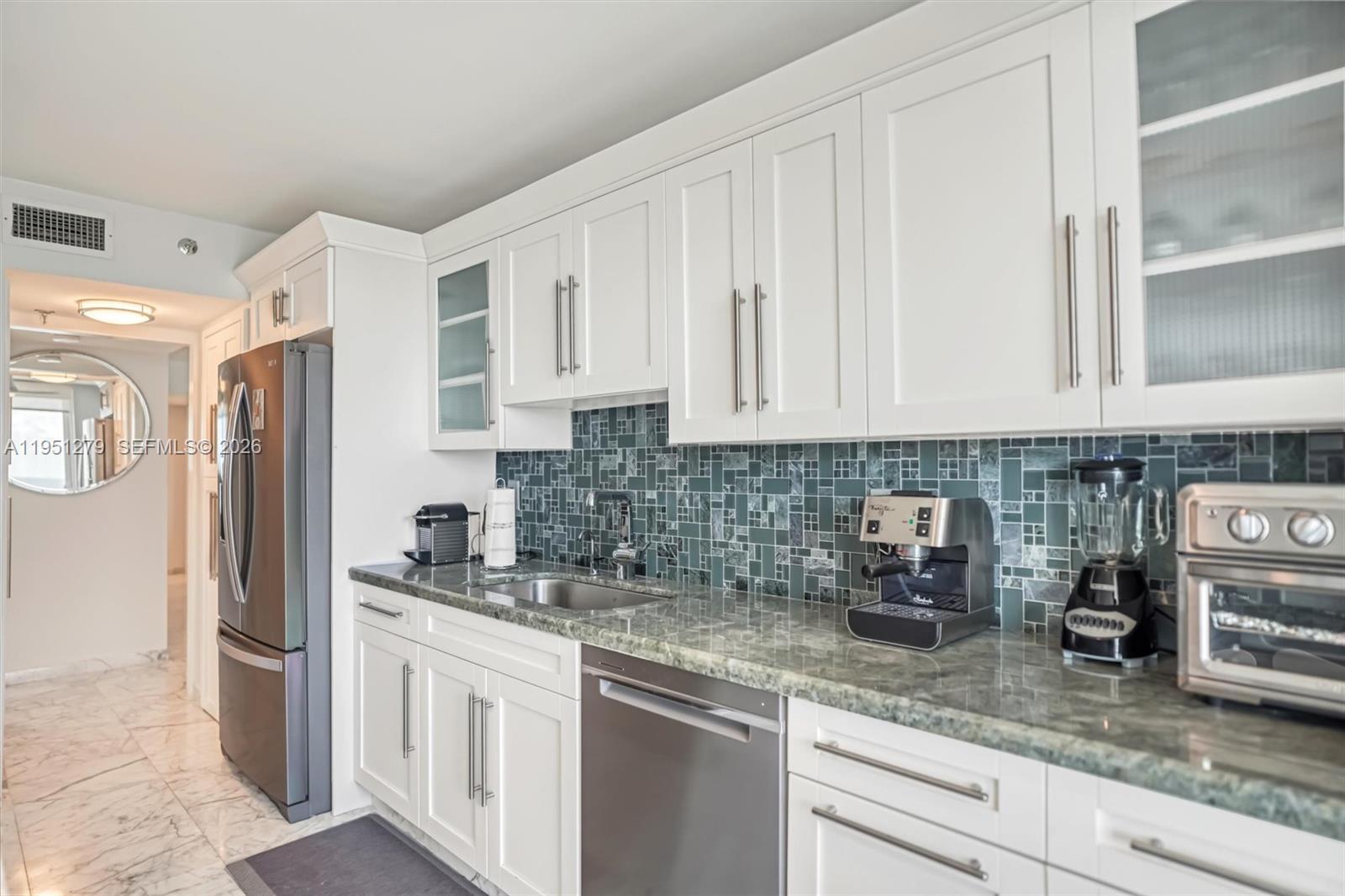 9341 Collins Avenue, Unit 201 Surfside, FL 33154 - Photo 3 of 34 a kitchen with stainless steel appliances granite countertop a refrigerator sink and cabinets