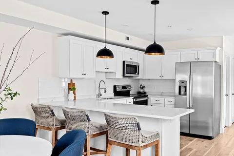 a kitchen with stainless steel appliances kitchen island granite countertop a table chairs and a refrigerator