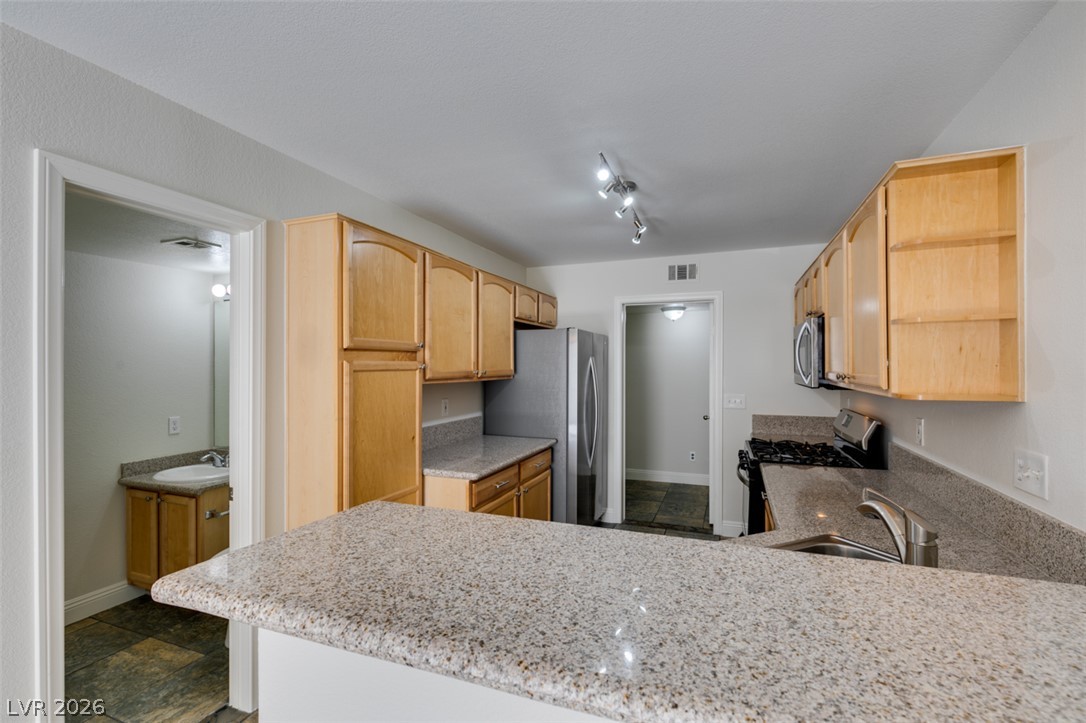 200 Luninborg Street Henderson, NV 89074 - Photo 21 of 40 Gleaming granite countertops define this well-appointed kitchen, featuring a gas range and sleek stainless steel appliances.
