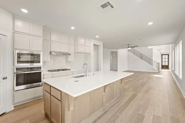 a kitchen with a sink a stove a refrigerator and white cabinets