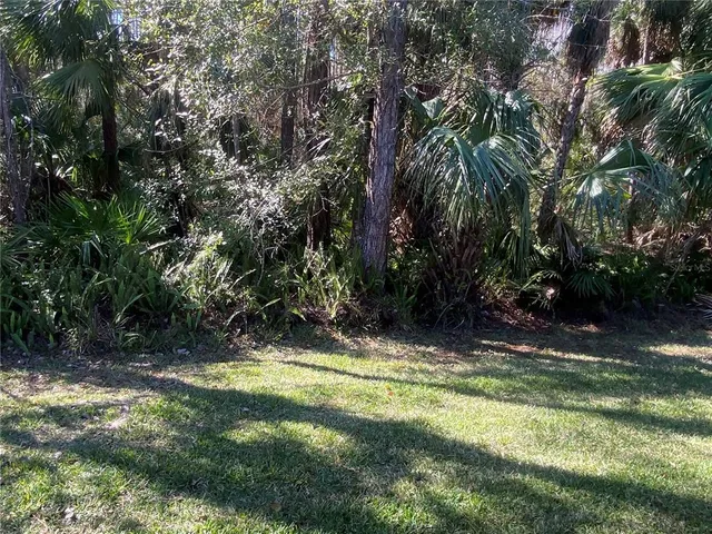 a view of a refrigerator in kitchen and empty room with wooden floor