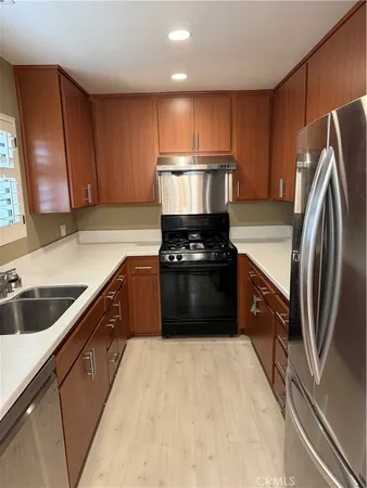 a kitchen with kitchen island granite countertop a refrigerator a sink a stove a microwave and wooden cabinets