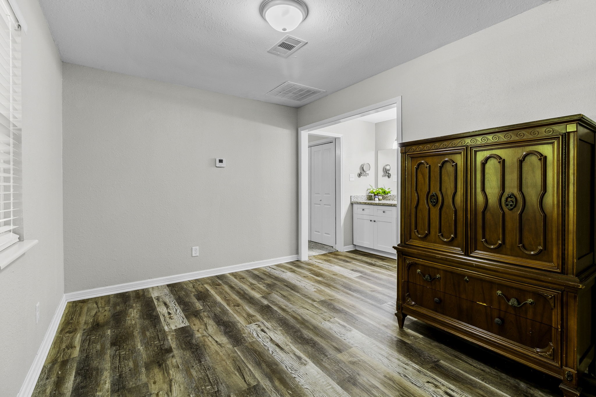 21 Red Oak Circle Point Blank, TX 77364 - Photo 15 of 32 This bright room features wood-look flooring, neutral walls, and a classic wooden cabinet. It leads to a bathroom with a modern vanity, perfect for a cozy and functional space.