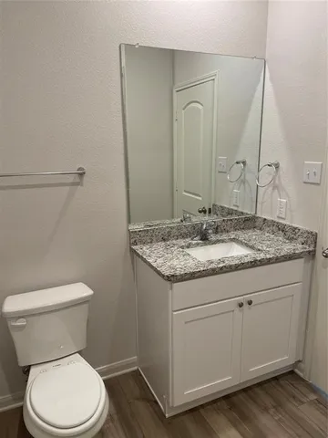 a bathroom with a granite countertop toilet sink and mirror