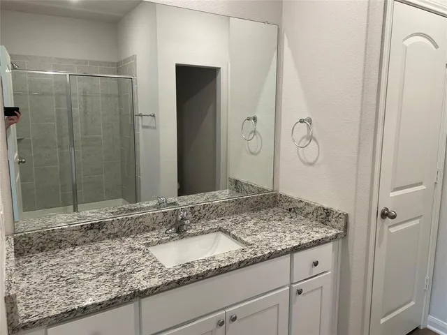 a bathroom with a granite countertop sink and a mirror