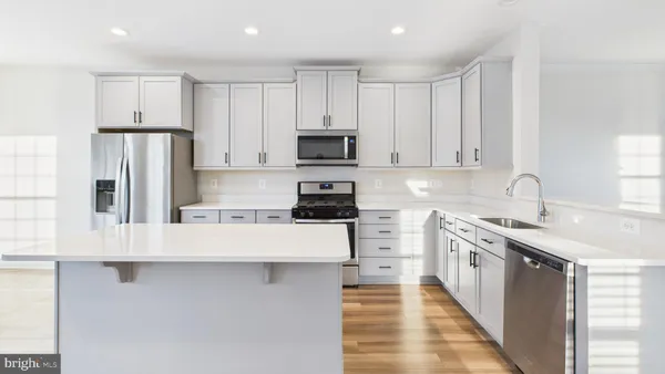 a hall with kitchen island white cabinets and wooden floor