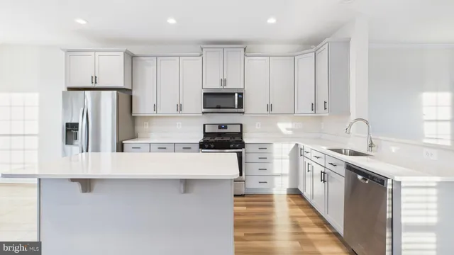 a hall with kitchen island white cabinets and wooden floor